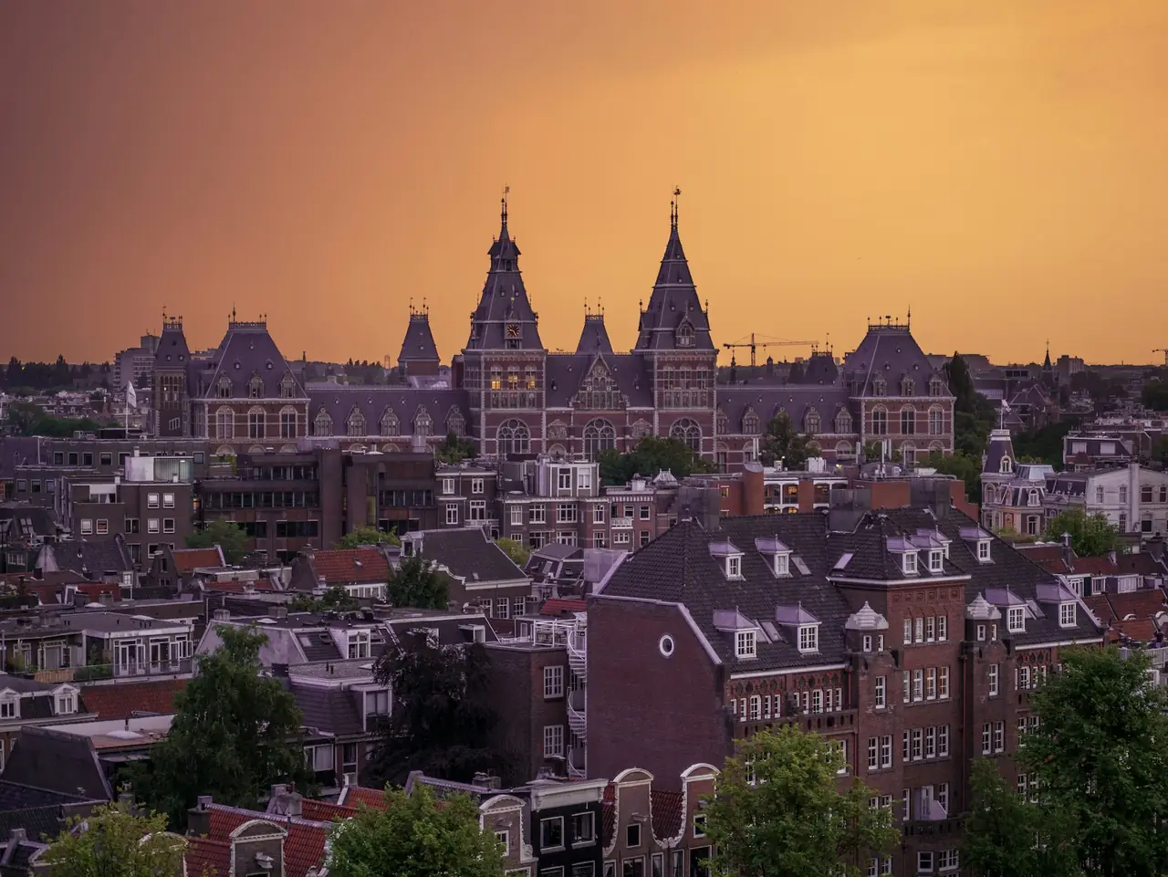 De daken van Amsterdam met het Rijksmuseum bij zonsondergang