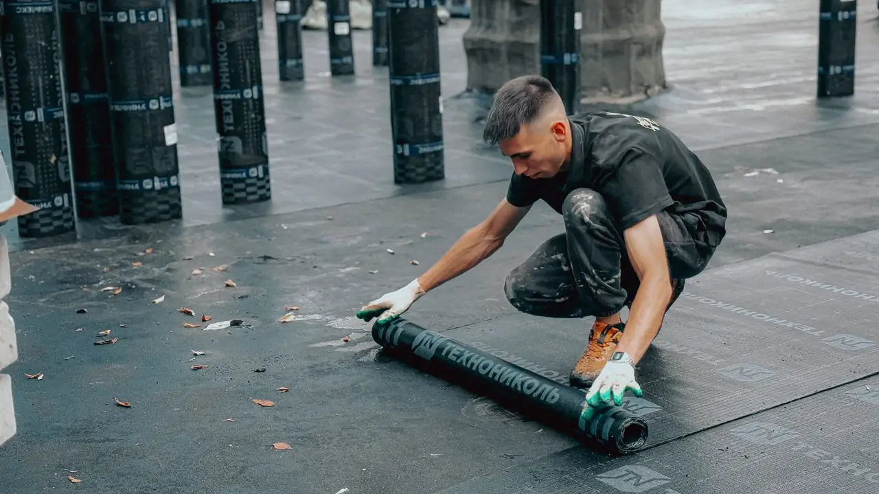 Dakdekker brengt een nieuwe dakbedekking aan op een plat dak