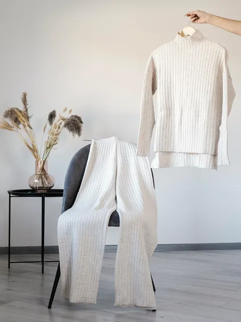 Kaschmirpullover und weite Hose auf einem Stuhl am Fenster