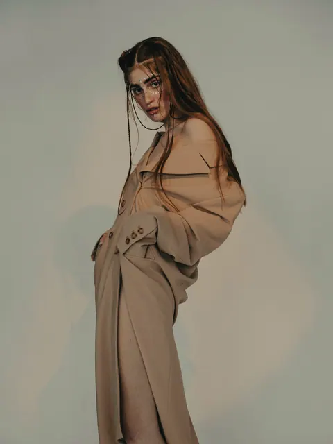 Model in einem langen kamelfarbenen Mantel