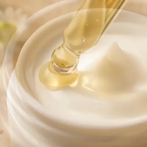 Ein Tropfen Serum fällt in einen Tiegel Saelis Creme